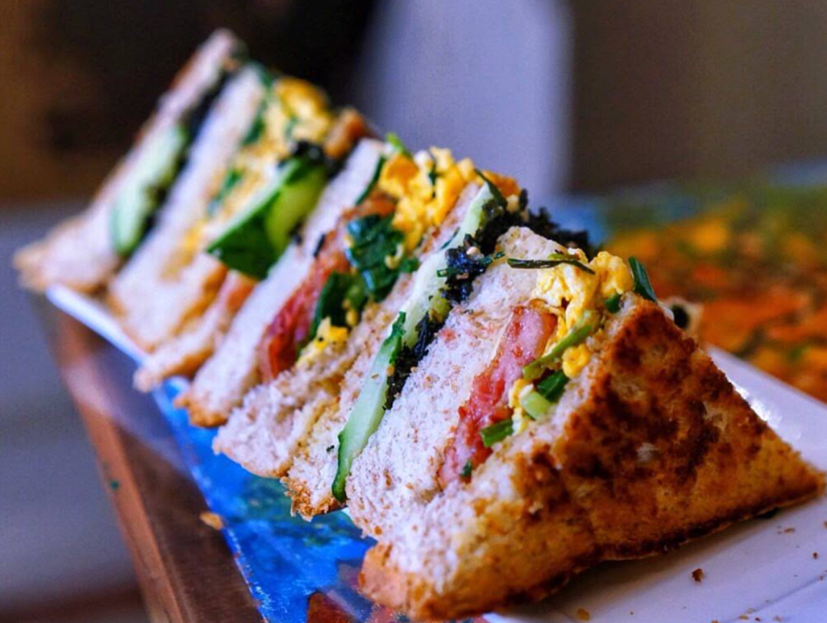The Happiness club sandwich, stacked with egg, tomato and cucumber